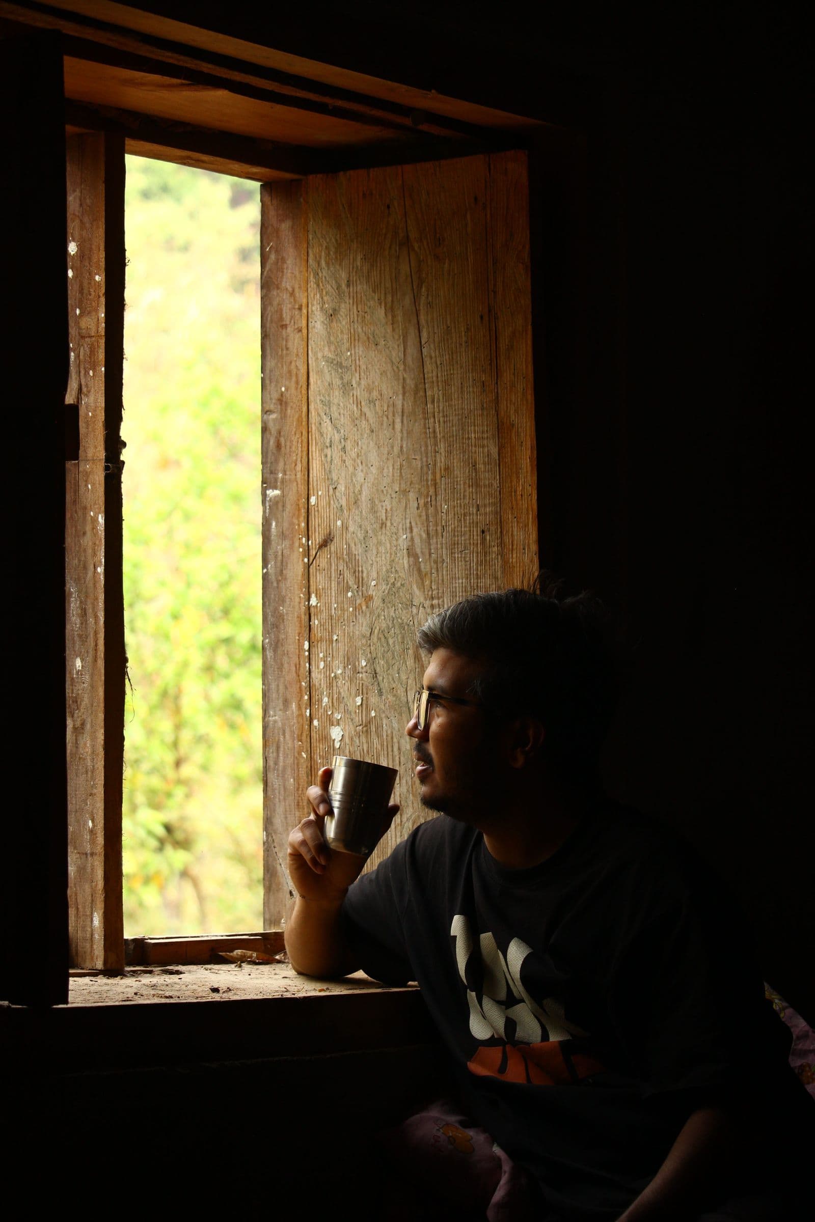 A person having coffee alone by a rustic wooden window