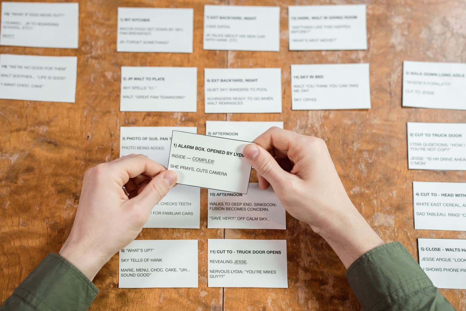 Hands arranging handwritten index cards on a wooden desk