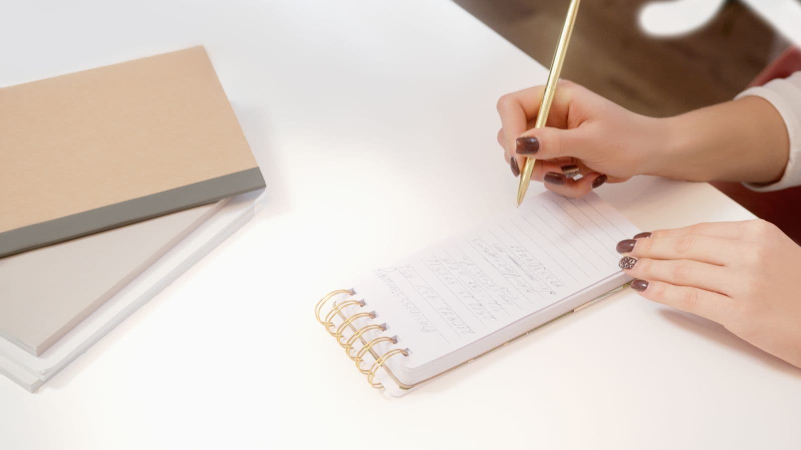 A hand writing a single line in a small spiral-bound notebook