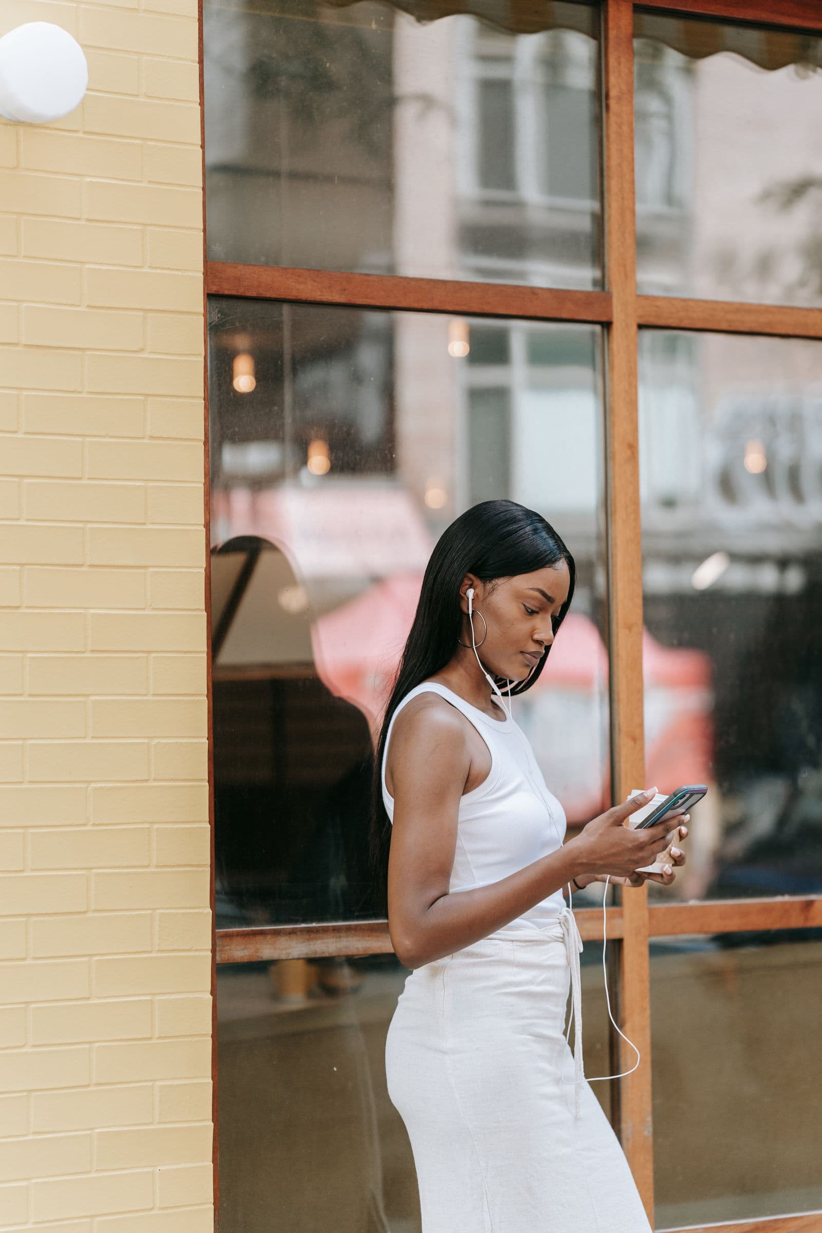A woman walking past a cafe, phone in hand